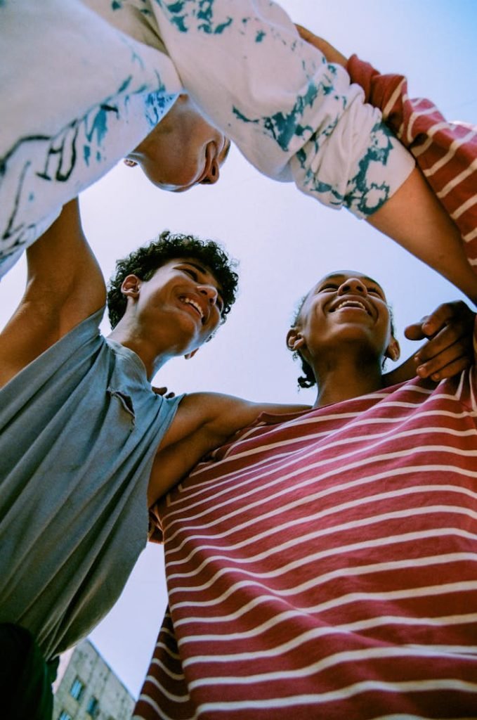 happy-young-teenage-boys-hugging-each-other-10536994 Happy group of teenagers enjoying a moment together under blue sky, symbolizing friendship and fun.
