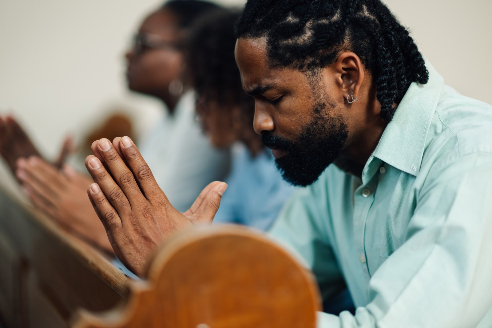 Black man praying with family in church pew
